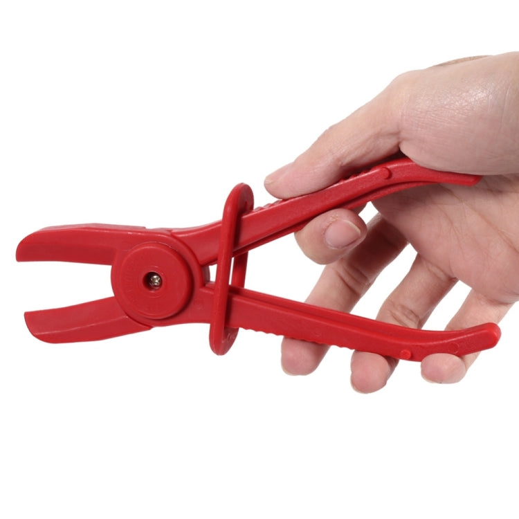 Red nylon hose clamp plier held in a hand, with central latch knob