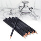 Graphite sketching pencil set angled on paper, dark pencils with sharpened graphite tips.