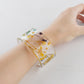 Hand wearing a clear resin floral cuff bracelet with dried botanicals