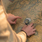 2-in-1 compass on a map with hands; clear body and black braided lanyard