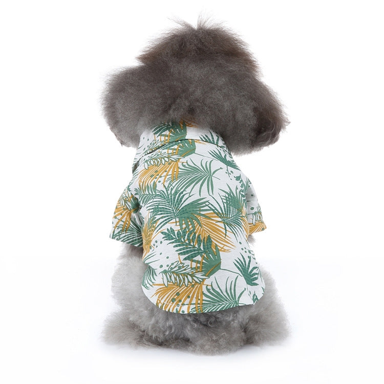 Dog summer shirt with green and gold tropical leaf print on white fabric.