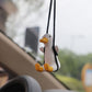 Small white duck car pendant hanging from two black cords, yellow beak and feet