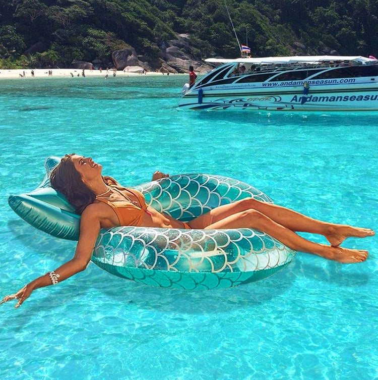 Turquoise mermaid swimming ring floating on clear ocean water