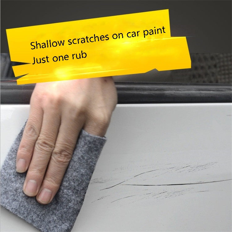 Hand holding a gray felt car scratch repair cloth pad against car paint.