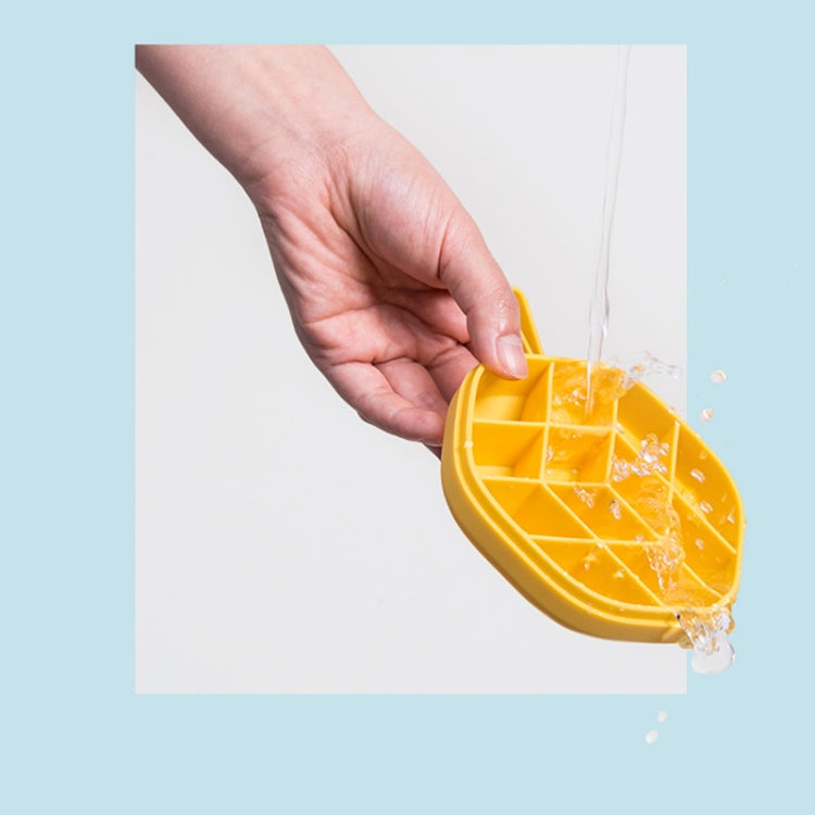 Yellow hexagonal ice cube tray pouring ice cubes, with hand holding lid