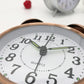 Close-up of copper alarm clock face with bold numerals and three clock hands