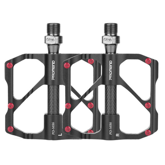 Black carbon fiber bicycle platform pedals, dual studs and threaded axle, red accents.