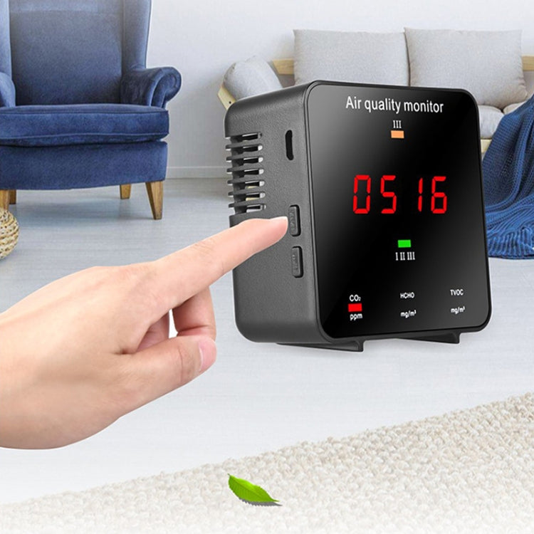 Portable air quality monitor with hand pointing at side controls and red 0.5/1.6 display