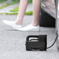 Portable black car inflatable air pump with hose on driveway near car wheel