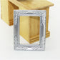 Miniature silver decorative dollhouse frame with detailed filigree edging and clear center
