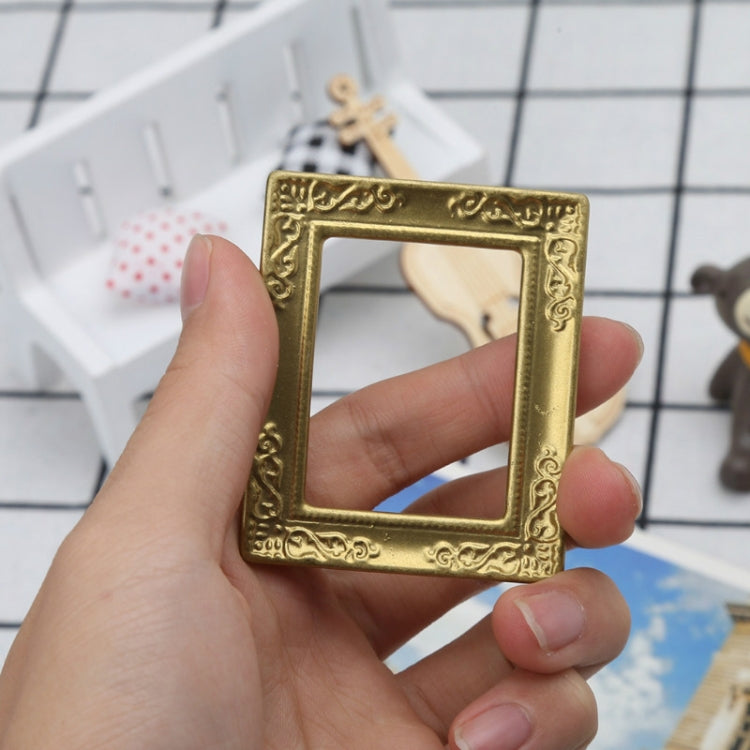 Miniature gold ornate dollhouse picture frame held in hand with empty center
