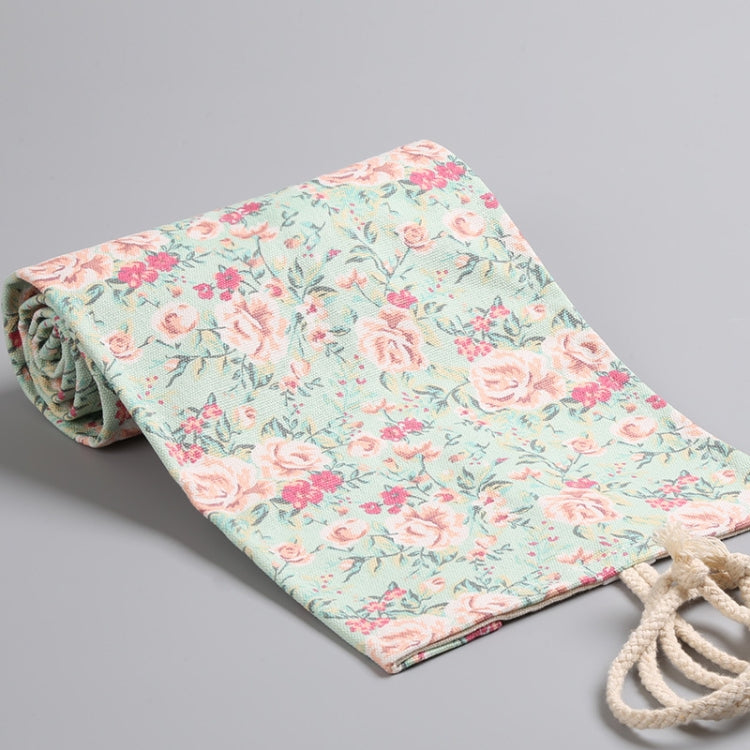 Floral canvas pen roll laid flat and tied with drawstring; pastel blue with roses.