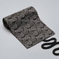 Black canvas pen roll bag with white leaf pattern, folded view with black tie cord visible