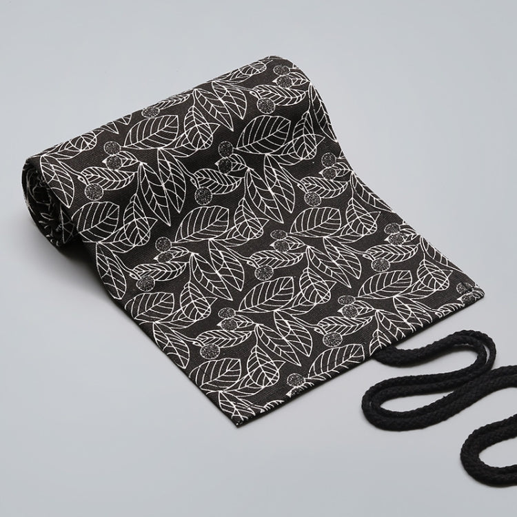 Black canvas pen roll bag with white leaf pattern, folded view with black tie cord visible