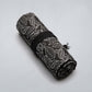 Rolled black canvas pen bag with white leaf pattern and tassel tie on the side