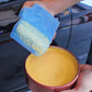 Blue microfiber sponge towel, thick folded pad held to apply wax or polish