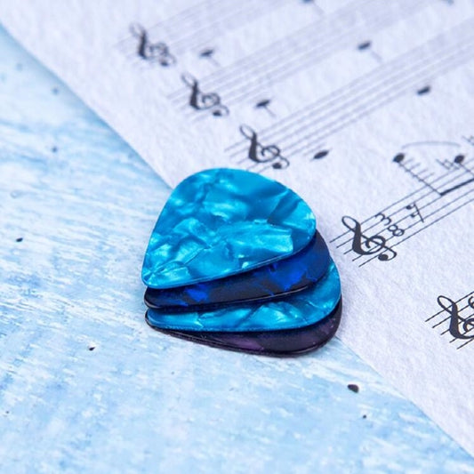 Guitar pick set, blue and purple triangular picks stacked on sheet music