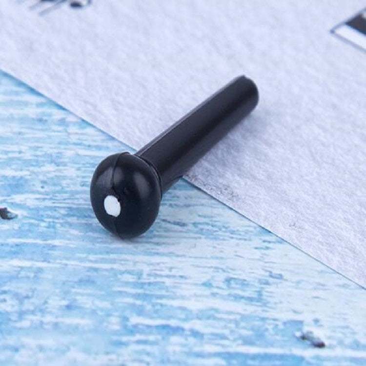 Black plastic guitar string nail with conical head, close-up on blue paper