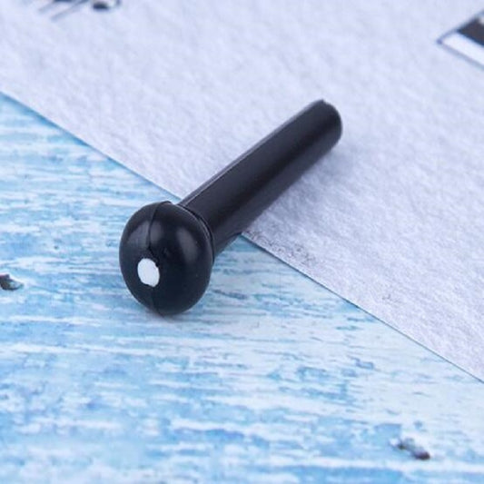 Black plastic guitar string nail with conical head, close-up on blue paper