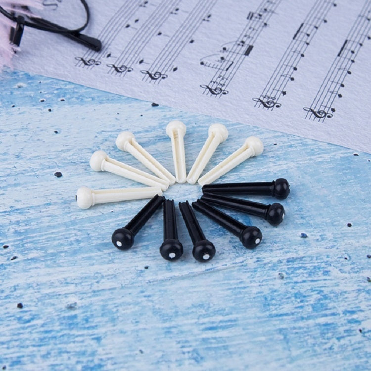 Assorted guitar string nails in white and black with plastic conical heads on blue paper