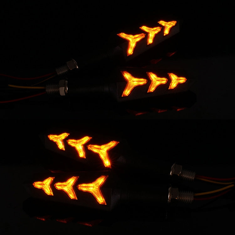 Two black motorcycle LED turn lamps glowing amber arrow patterns with wiring leads