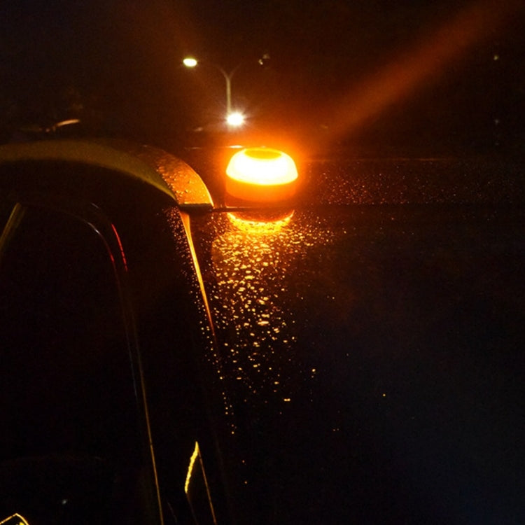 Amber flashing LED warning light illuminating wet road and car surface