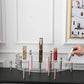 3-tier clear acrylic cosmetic display stand with silver posts holding small bottles