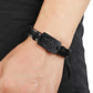 Black woven leather bracelet on wrist with wolf-head metal clasp