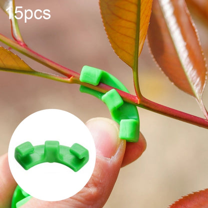 Green U-shaped plant training clips gripping a plant stem