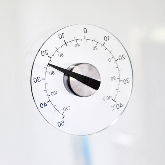 Round outdoor thermometer dial with black indicator hand on clear glass face