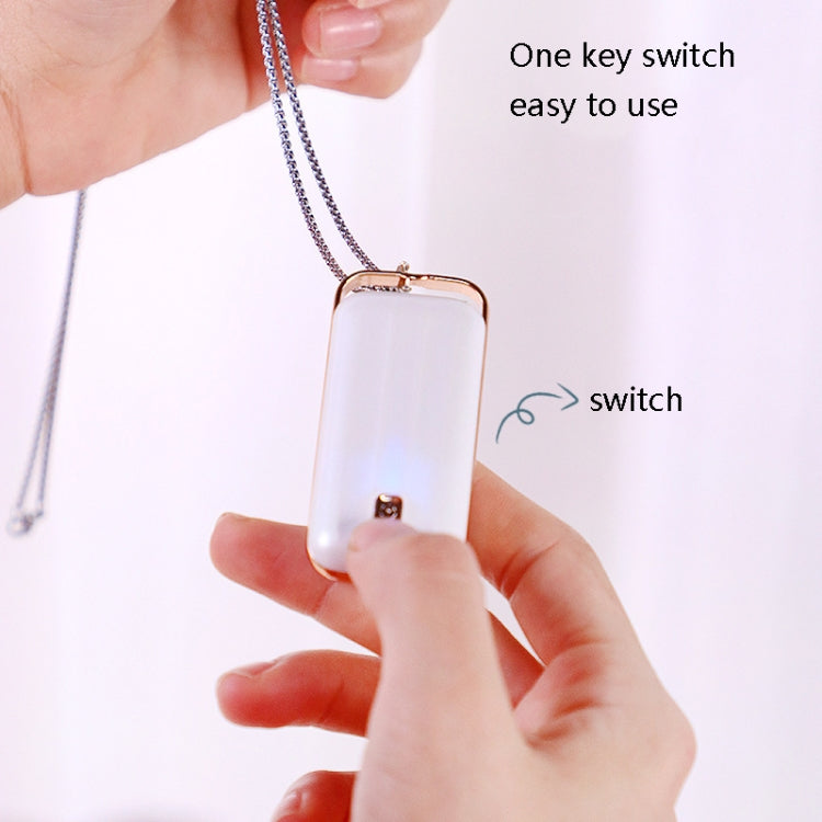 Hanging air purifier on a silver chain with rose-gold top, held in hand