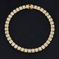 Gold-tone tennis bracelet with continuous square rhinestone stones, round profile.