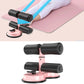 Black sit-up aid with pink suction base, padded rollers, and ankle supports