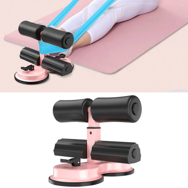 Black sit-up aid with pink suction base, padded rollers, and ankle supports
