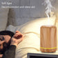 Light wood-grain aromatherapy air purifier with visible steam, rounded cylinder with teal base ring