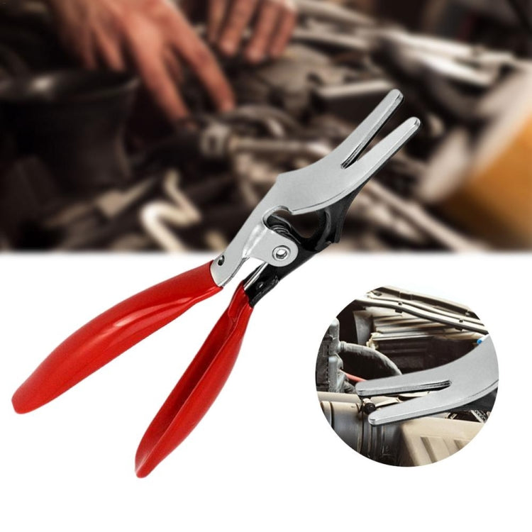 Fuel pipe separating plier in use on engine bay, red handles and metal jaws