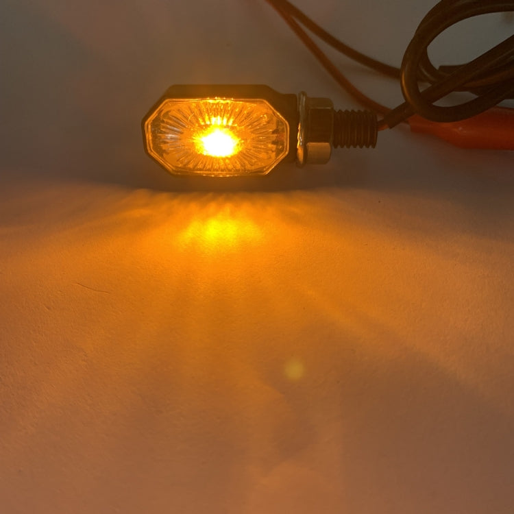 Lit LED motorcycle turn signal light showing bright amber glow through clear lens
