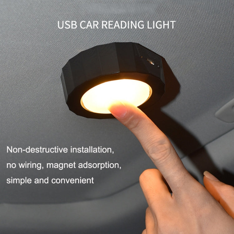 Black octagonal LED reading light with warm glow and finger touching top