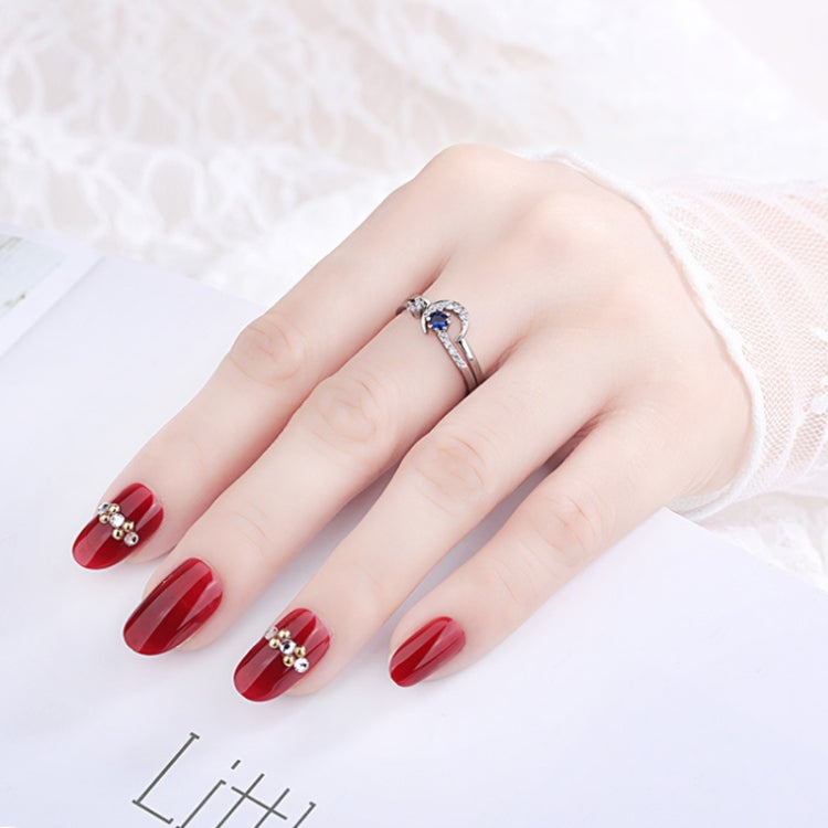 Silver-tone open ring with blue center stone and clear crystals, worn on hand