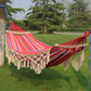 Double outdoor hammock with pink striped fabric, dark blue base, and cream fringe tassels.