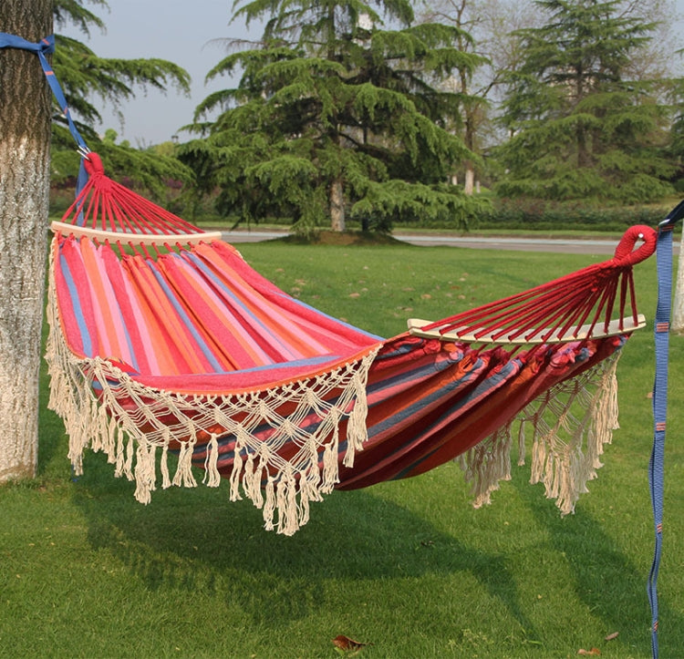 Double outdoor hammock with pink striped fabric, dark blue base, and cream fringe tassels.