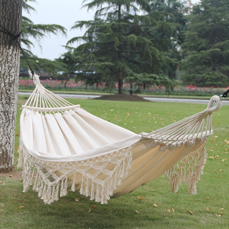 Double white canvas hammock with braided net seat and long fringe tassels.