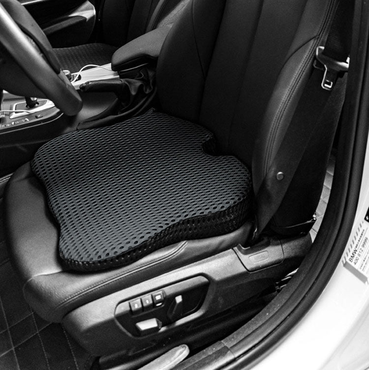 Black car seat cushion installed on vehicle seat, textured breathable mesh surface visible