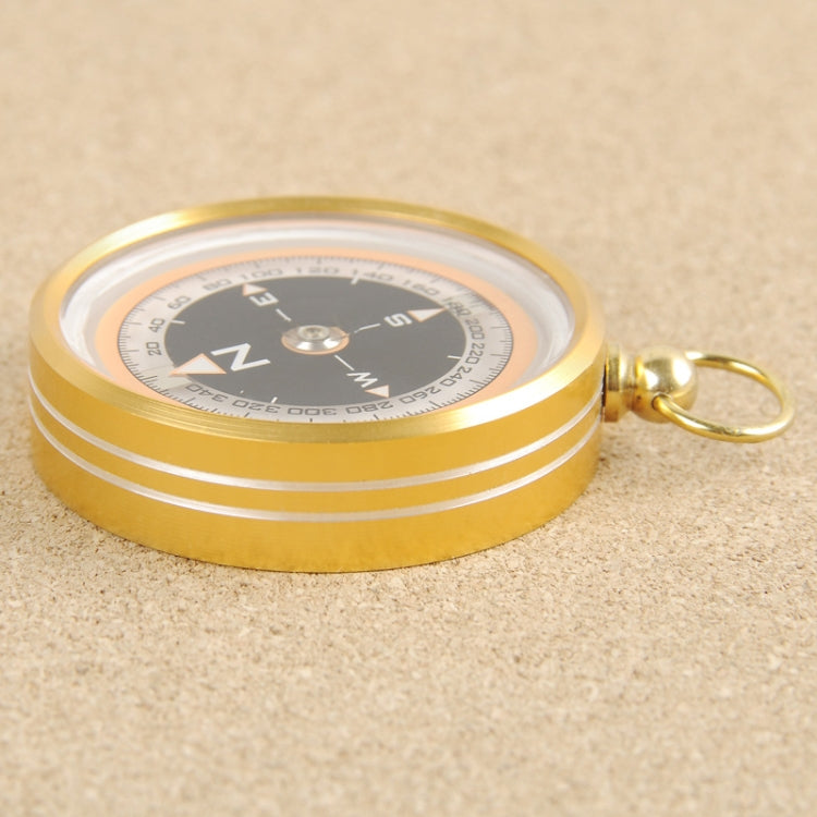 Gold metal pocket compass with black dial, clear cover, and keyring attachment.