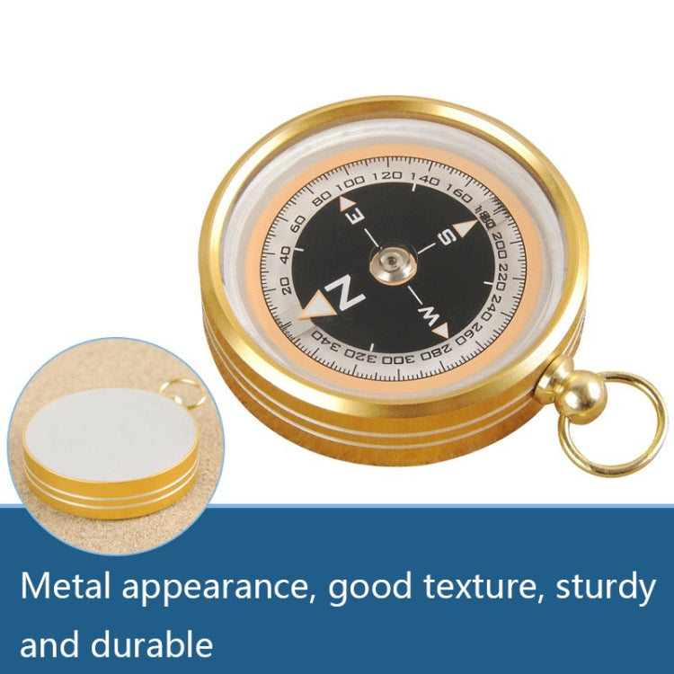 Gold metal outdoor compass with black dial, clear window, and keyring loop.