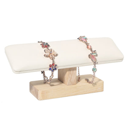 T-shaped jewelry display stand with white padded bar and light wood base, for bracelets