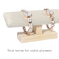 T-shaped jewelry display stand with beige fabric padded bar and light wood base, for watches