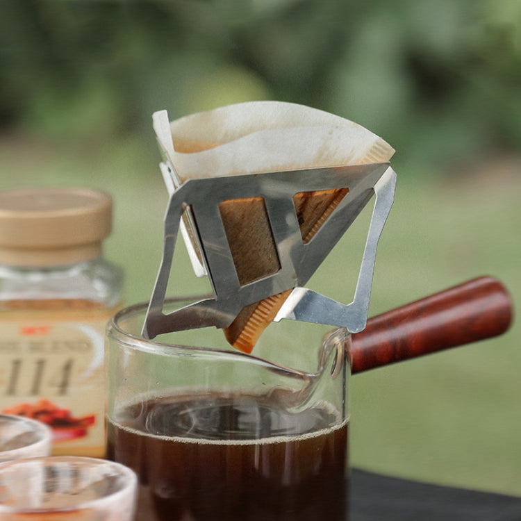 Stainless steel folding coffee grounds filter funnel with wooden handle over glass carafe