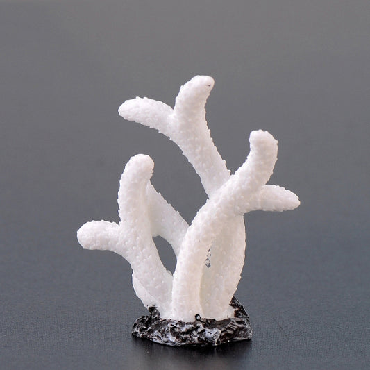 White branching resin coral aquarium ornament on textured black rock base.
