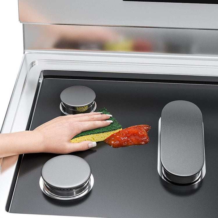 Black 5-hole stove protective cover pad being wiped clean with a sponge over burners